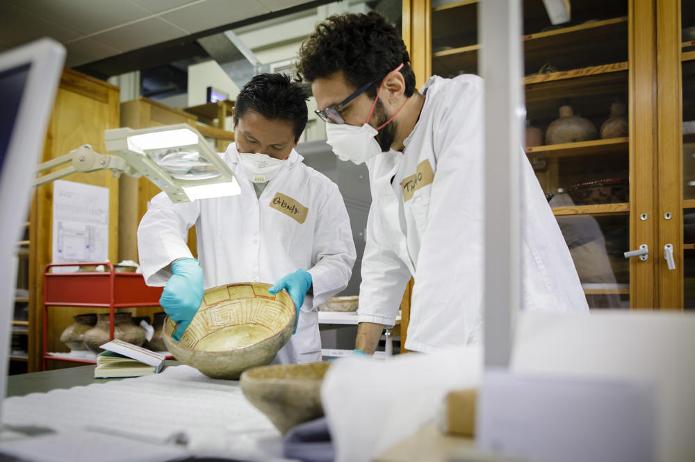 Untersuchen eine Baniwa-Keramik aus der Sammlung des Ethnologischen Museums: Thiago da Costa Oliveira (re.) und Orlando Fontes, ein Forscher und Vertreter von der indigenen Gruppe der Baniwa beim Workshop „Geteiltes Wissen“.