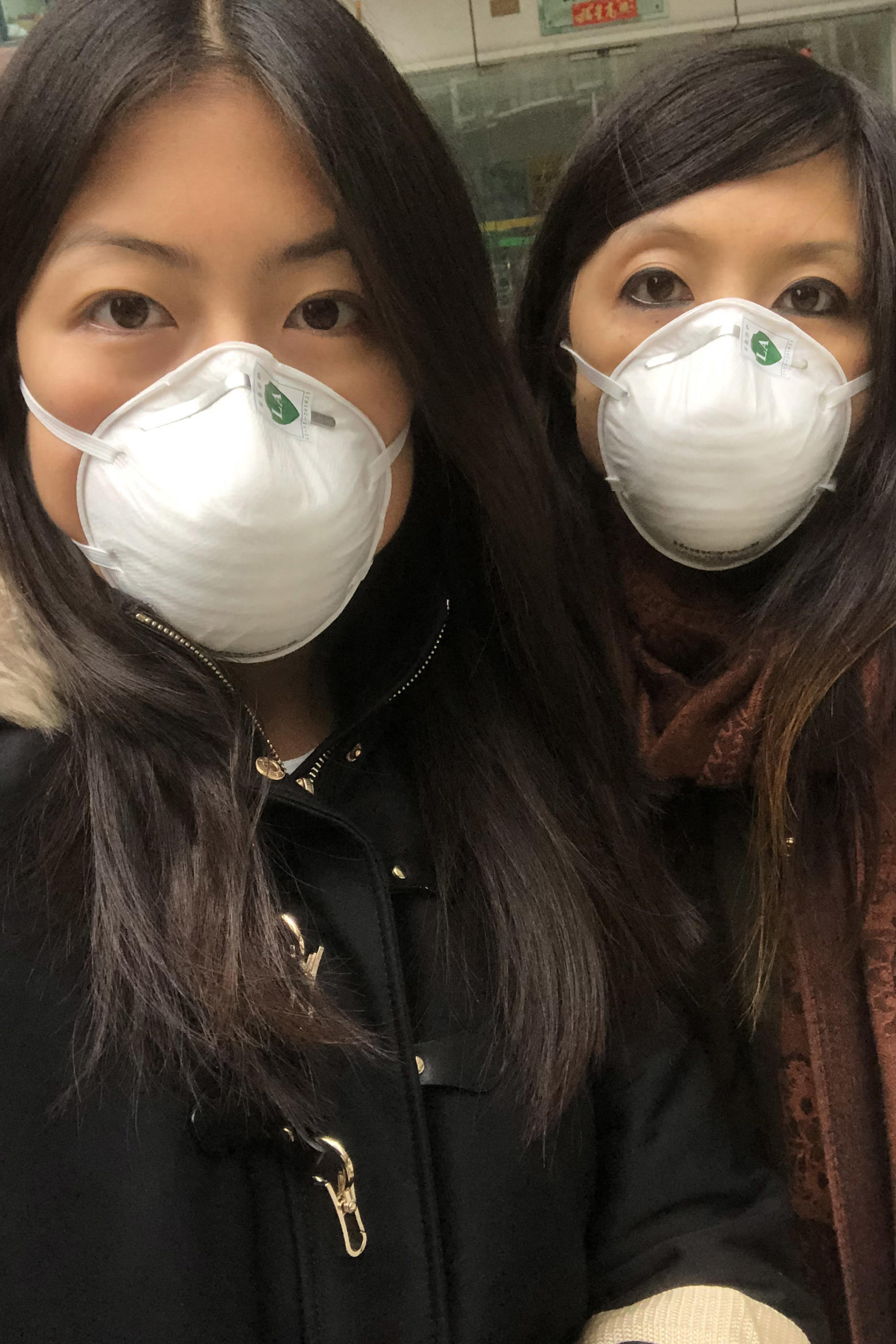 Masks on at all times: Vivi Feng (left) and her sister in Shanghai. Vivi Feng is now back in Germany.
