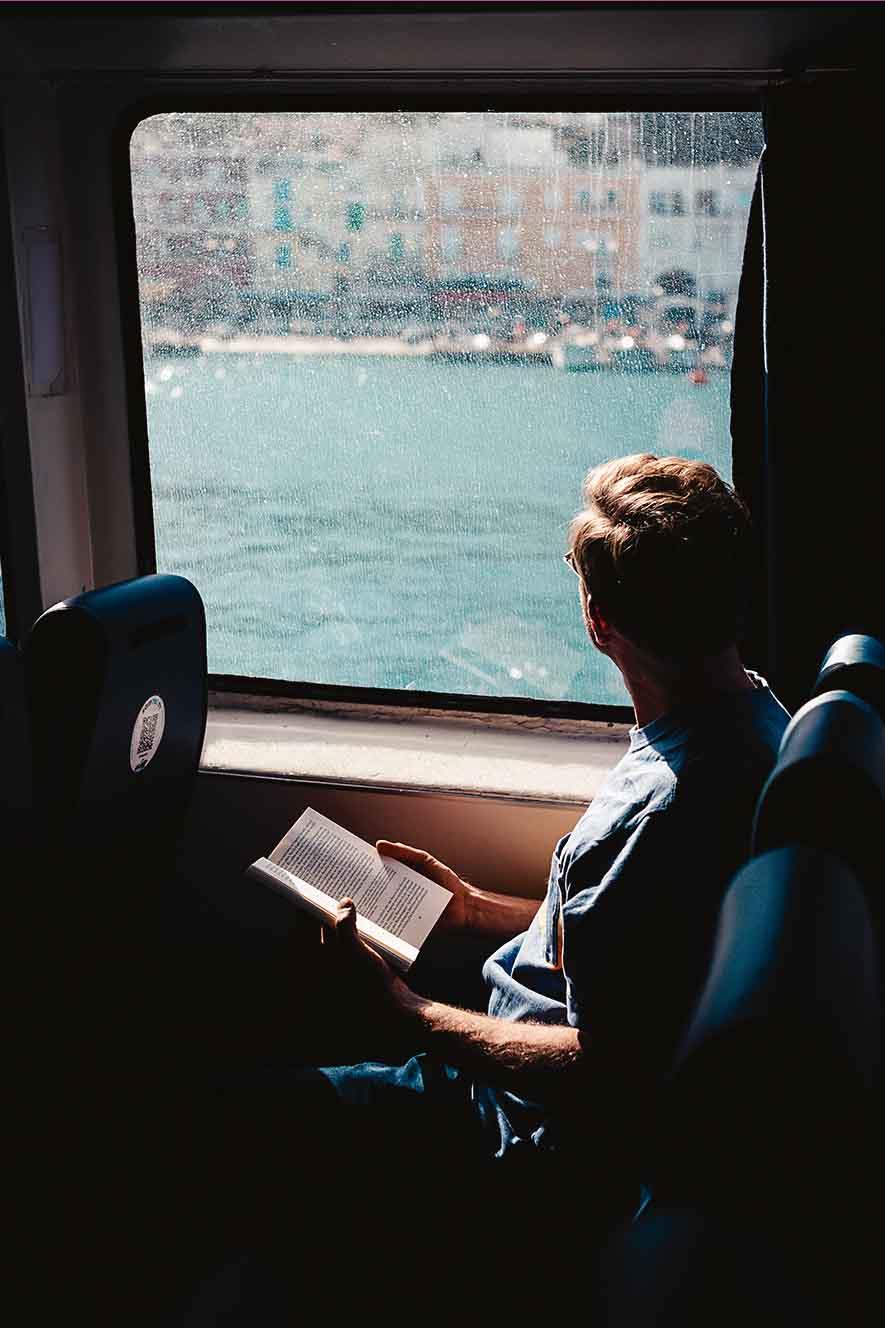 Auf Reisen lesen und Gedanken schweifen lassen, ist ein Luxus, gerade auch in Zeiten, in denen Smartphones und deren Anwendungen unsere gesamte Aufmerksamkeit einzufordern scheinen: ein Reisender auf der Fähre von Capri nach Neapel.